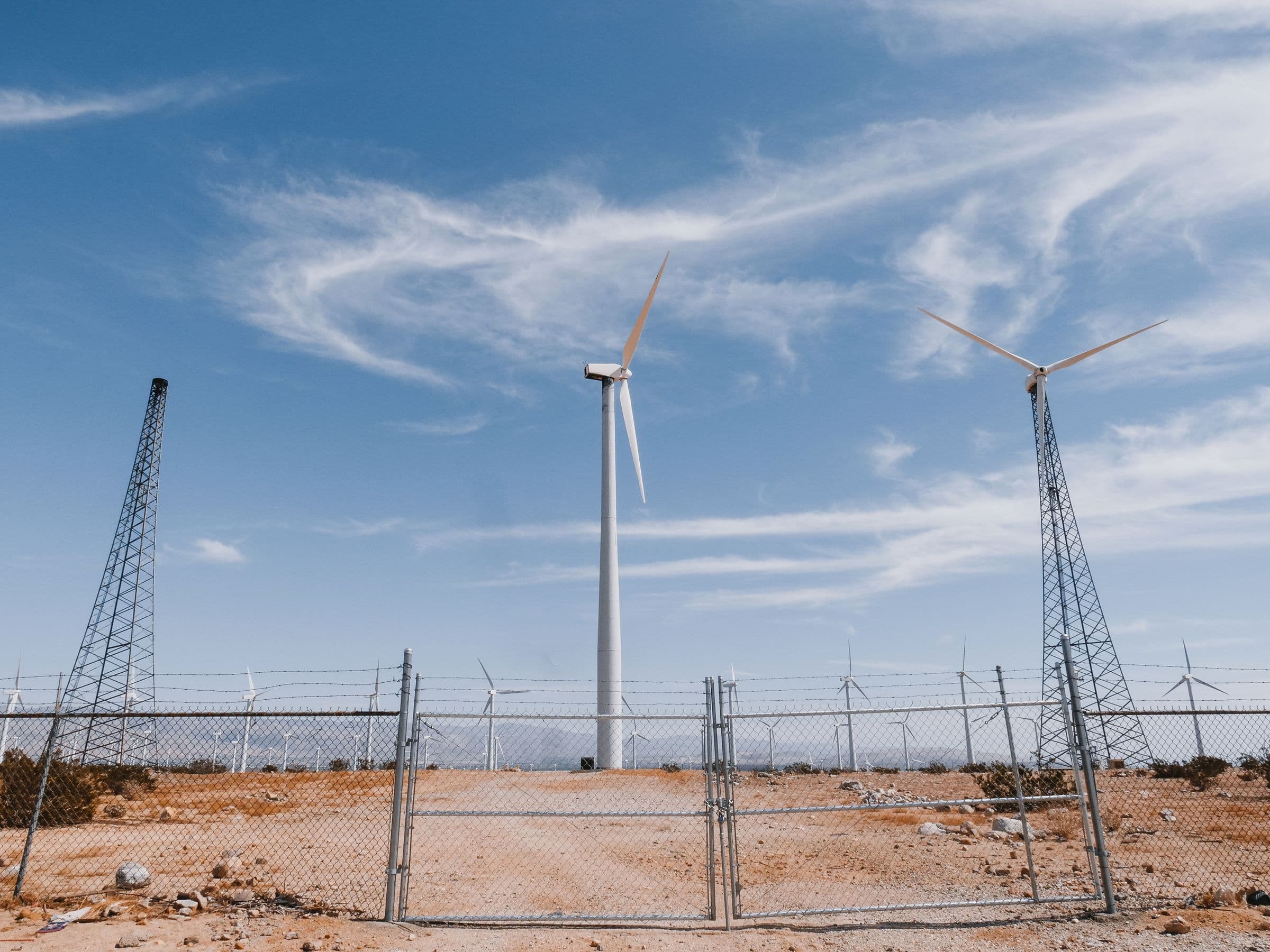 Wind turbines and transmission towers in a desert landscape.