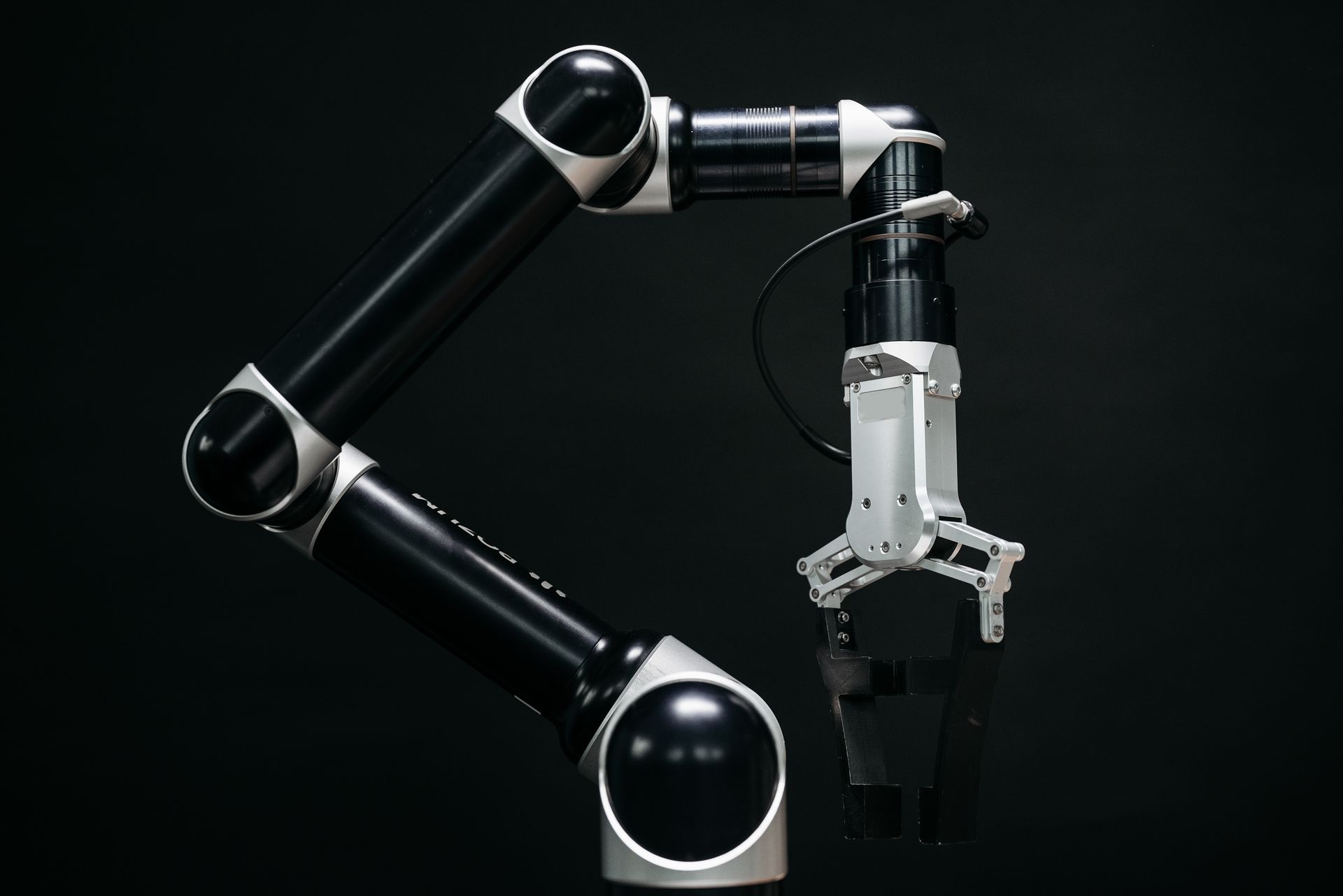 A robot arm with a two-finger gripper against a dark background.